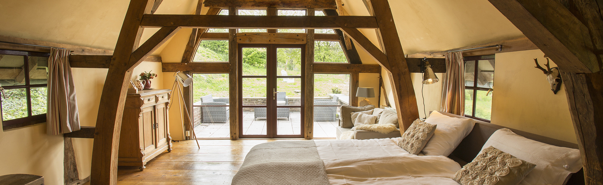 Sfeervolle slaapkamer onder een schuin dak met houten balken. 