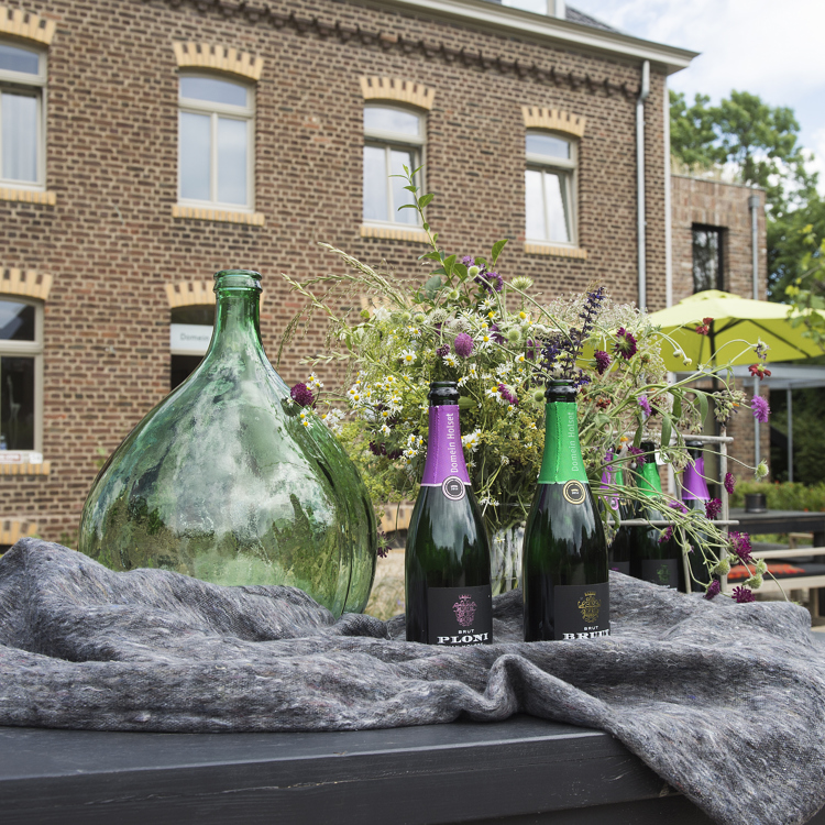 Twee flessen wijn op tafel met domein holset op de achtergrond. 