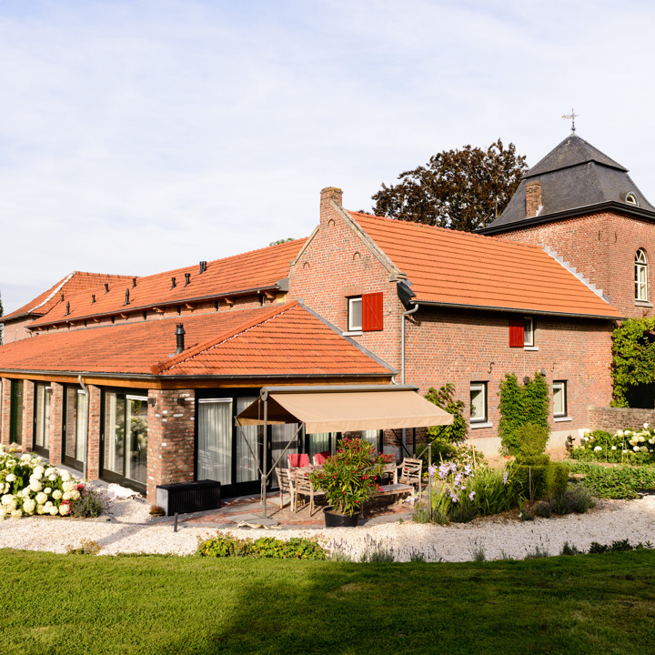 Buitenaanzicht van voormalige boerderij omringd door een mooie tuin. 