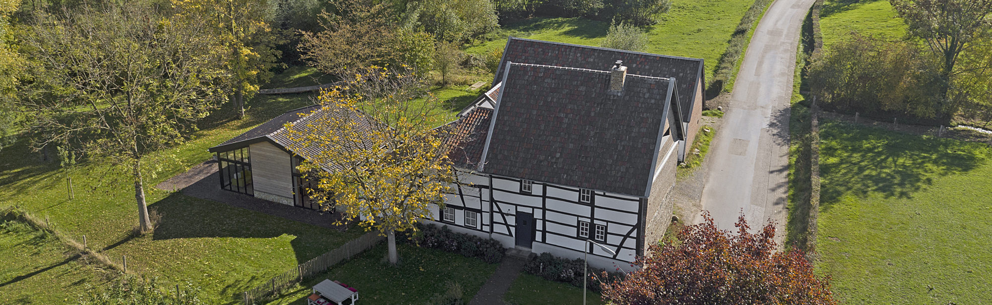 Bovenaanzicht van een vakwerkhuis in een groene omgeving