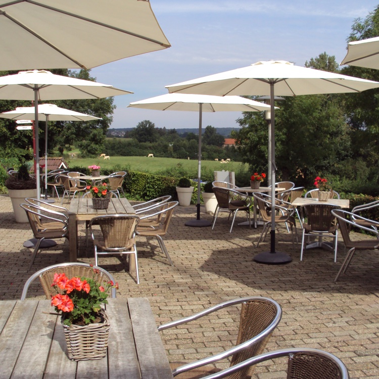 Zonnig terras met diverse tafels en parasols. 