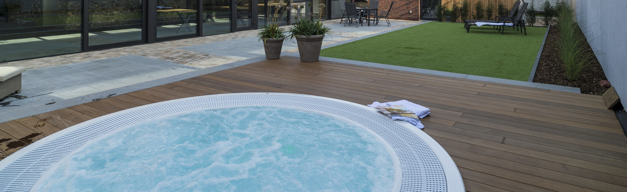 Luxe binnenplaats van hotelkamer met een bubbelbad, ligstoelen en een terras. 