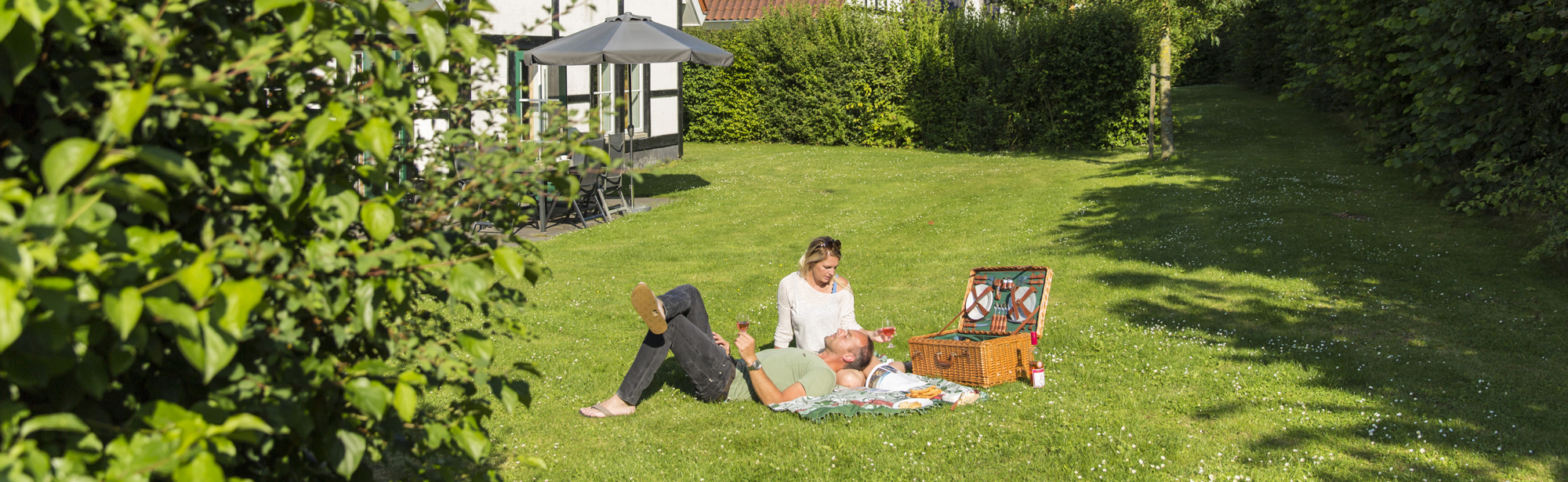 Gezin met picknickmand in de tuin aan het genieten van de zon. 