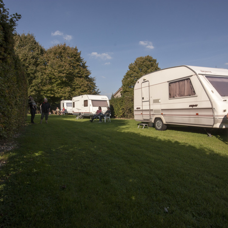 vrouw zit in de zon te genieten voor haar caravan. 