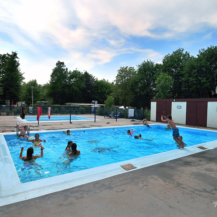 Kinderen spelen in buitenzwembad op de camping. 