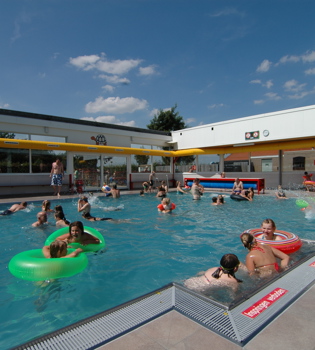 Vol buitenzwembad met spelende kinderen op een zomerse dag. 