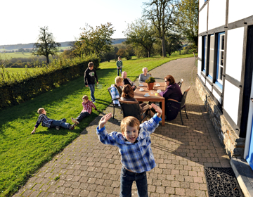 Kinderen spelen in het gras terwijl ouders gezellig bijkletsen aan tafel