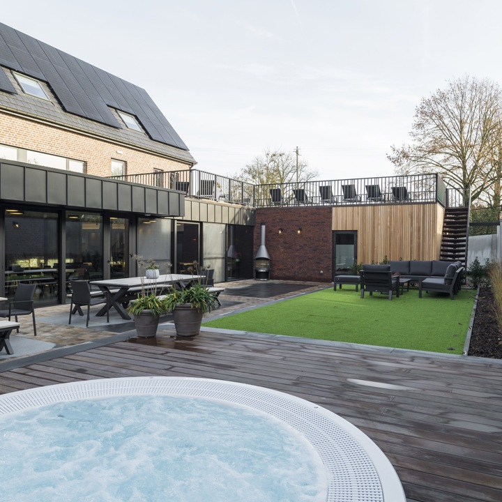 Luxe binnenplaats van hotelkamer met een bubbelbad, ligstoelen en een terras. 