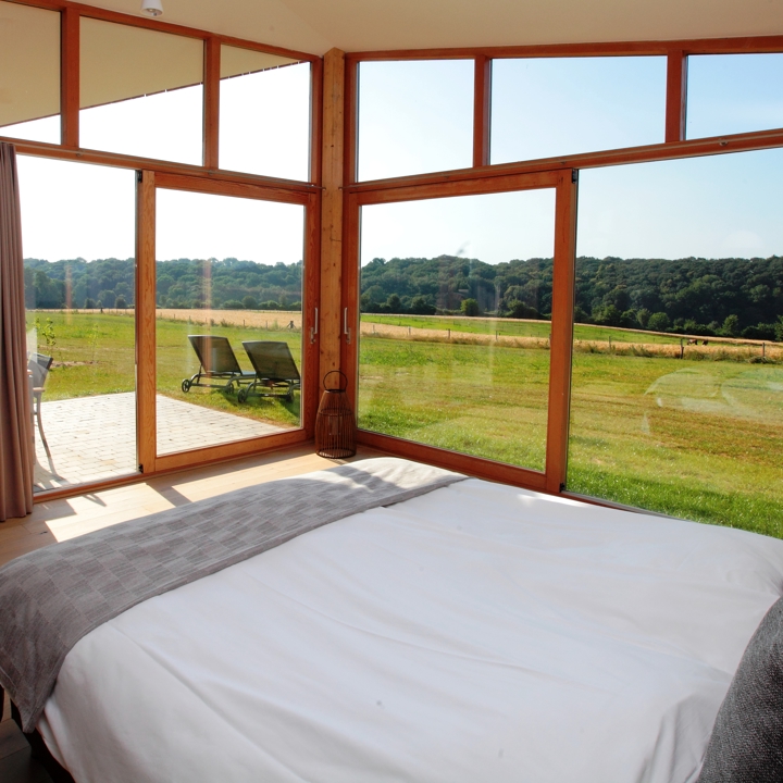 Een bed in een kamer met ramen en uitzicht over het landschap