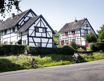 Fietsers fietsen langs vakwerkhuizen