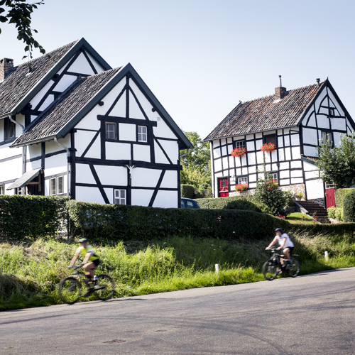 Fietsers fietsen langs vakwerkhuizen