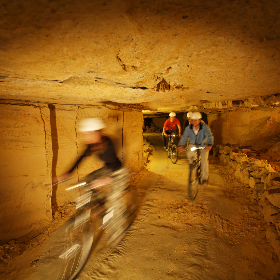 Mensen mountainbiken in de grotten van Valkenburg