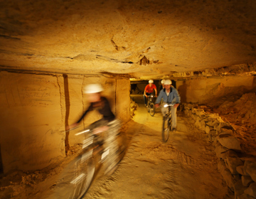 Mensen mountainbiken in de grotten van Valkenburg