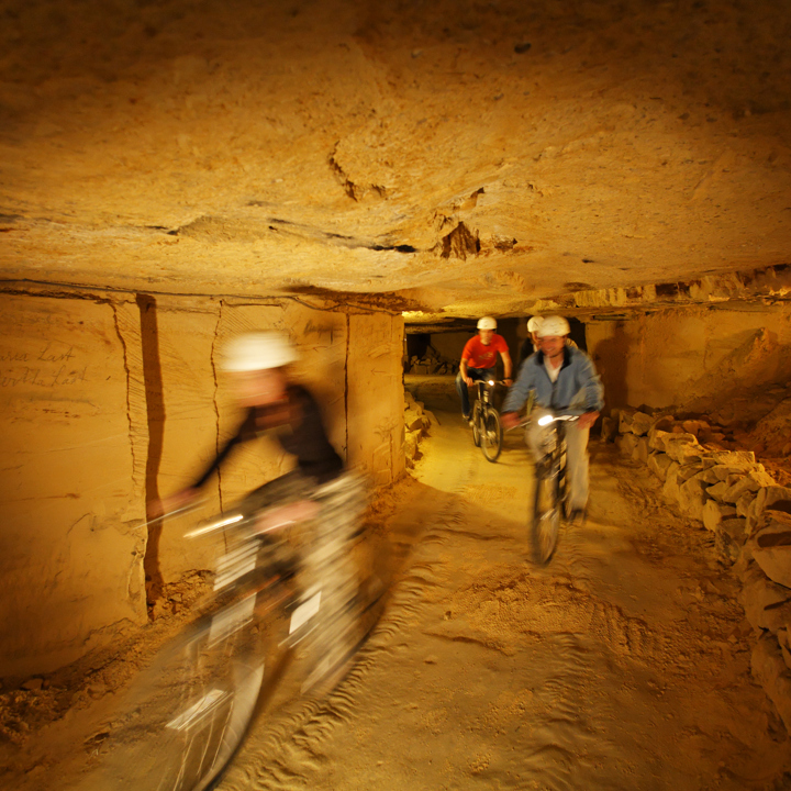 Mensen mountainbiken in de grotten van Valkenburg