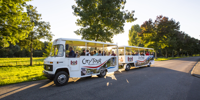 Treintje van Citytours rijdt over weg naast weiland op een zonnige dag