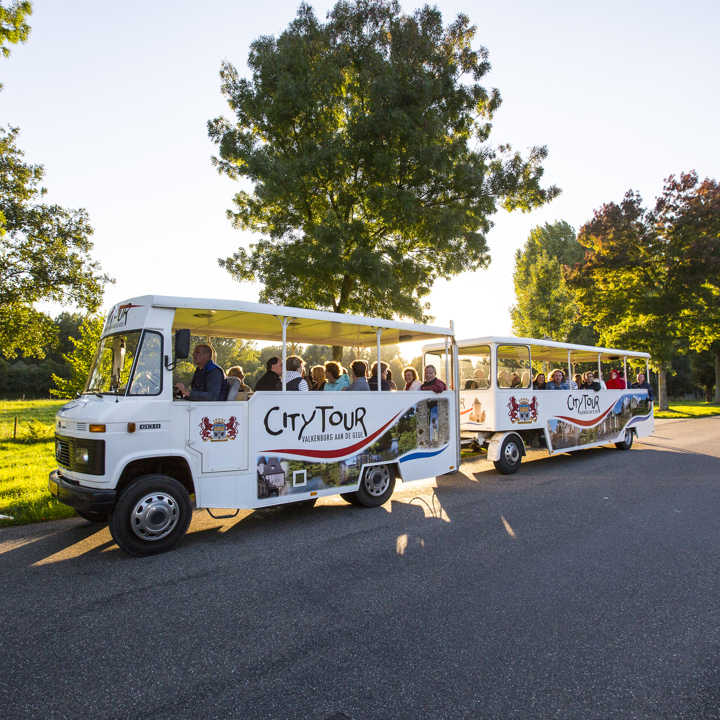 Treintje van Citytours rijdt over weg naast weiland op een zonnige dag