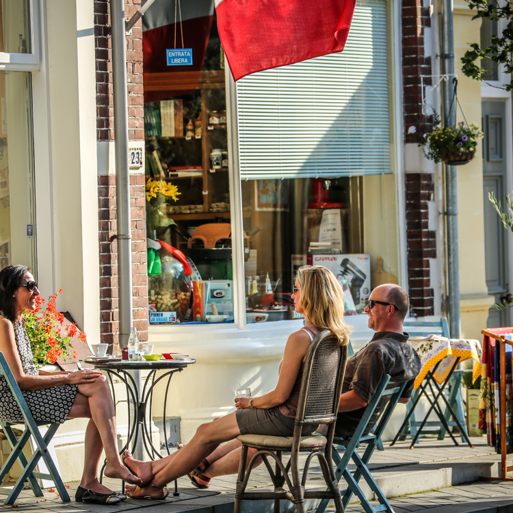 Mensen zitten op houten klapstoeltjes voor winkeletalage in Valkenburg