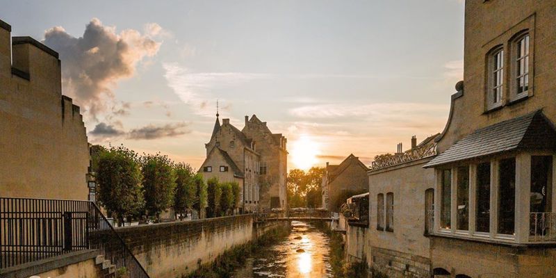 Beeld van Valkenburg met ondergaande zon vanaf met bloemen versierde brug richting Geulpoort