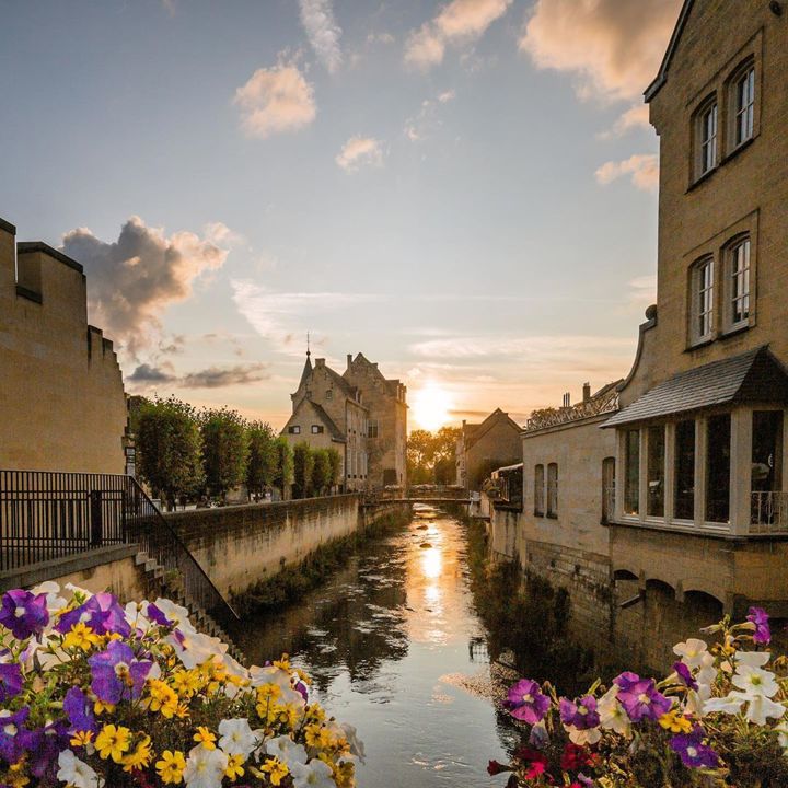 Beeld van Valkenburg met ondergaande zon vanaf met bloemen versierde brug richting Geulpoort