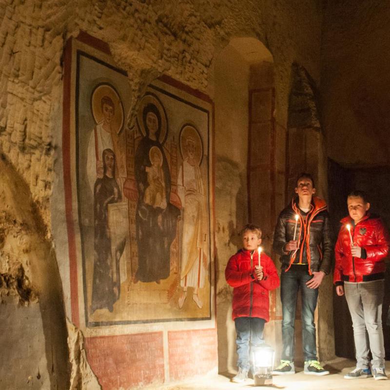 Personen met kaarsjes tijdens een rondleiding door de Romeinse Katakomben in Valkenburg