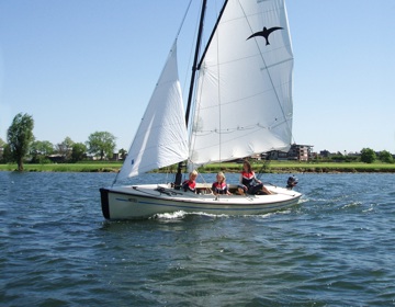 Een zeilboot met kinderen op het water 