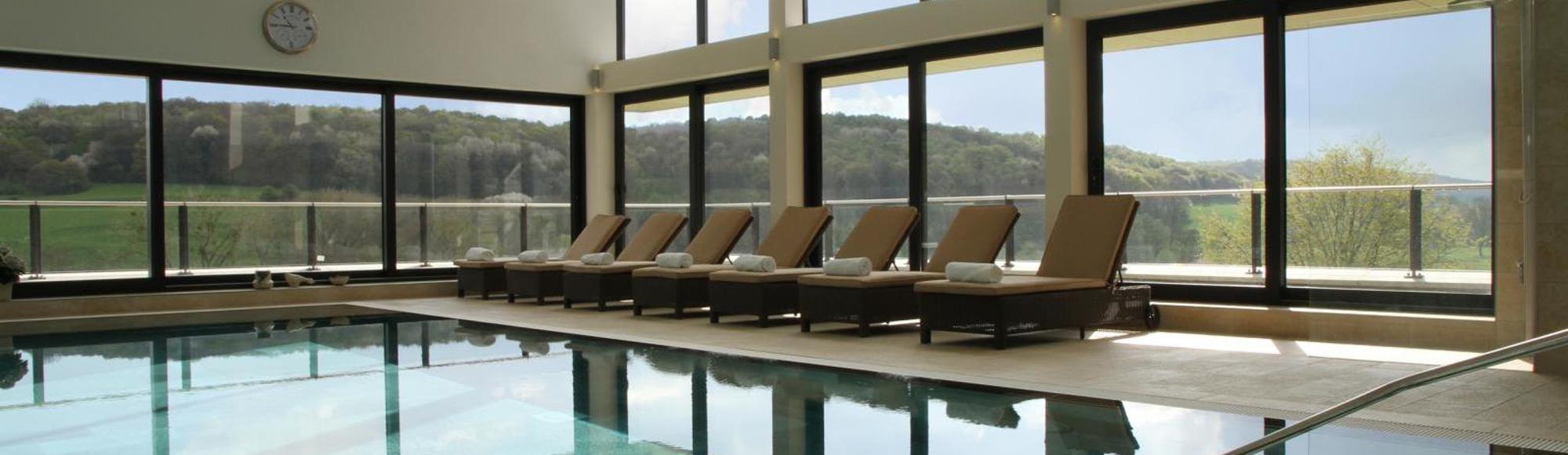 Ligbedden bij binnenzwembad en panorama uitzicht Hotel Klein Zwitserland