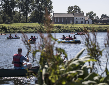 Mensen in verschillende soorten bootjes op de Maas op een zonnige dag