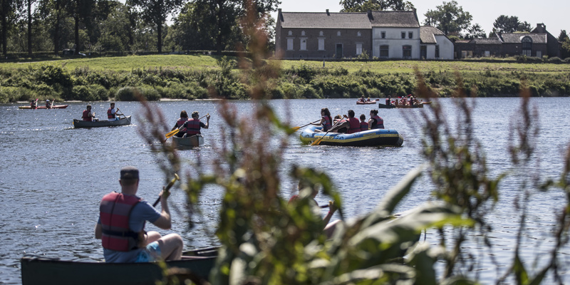 Mensen in verschillende soorten bootjes op de Maas op een zonnige dag