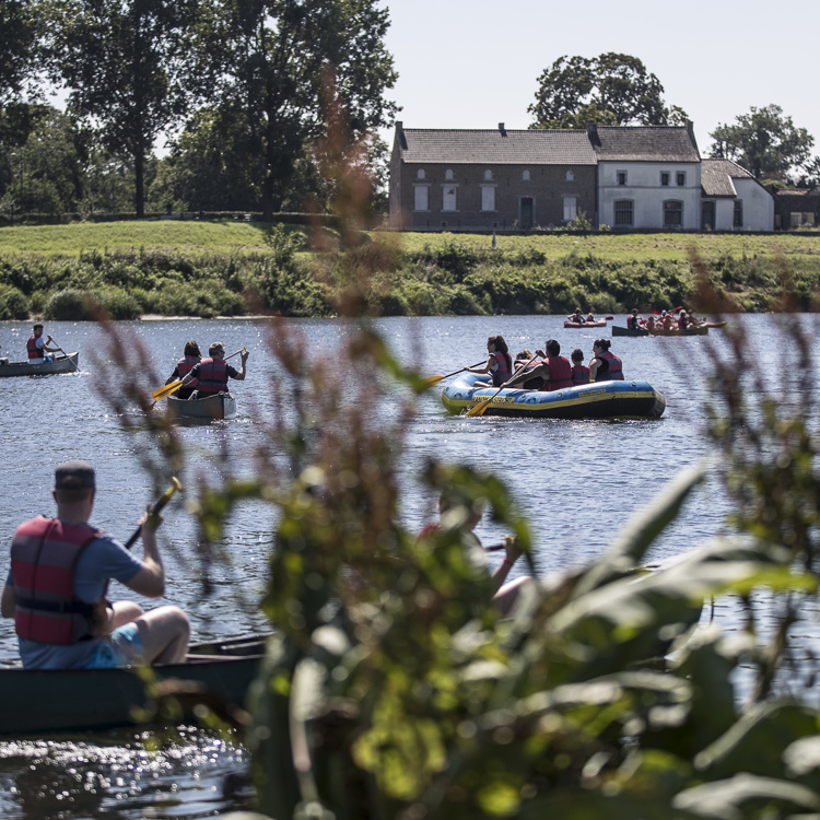 Mensen in verschillende soorten bootjes op de Maas op een zonnige dag