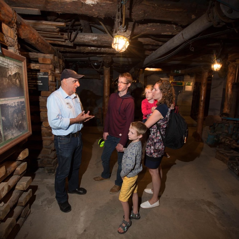 Gids geeft rondleiding aan gezin in het Mijnmuseum Beringen in België