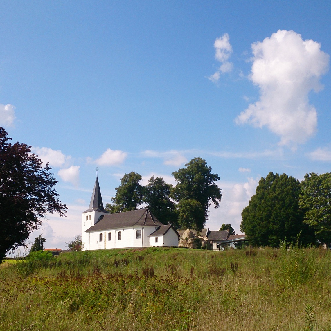 Het witte Clemenskerkje in Brunssum, vanuit de weide er omheen gefotografeerd