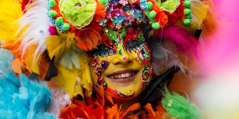 Vrouw draagt veelkleurig pakje en schminck met Carnaval