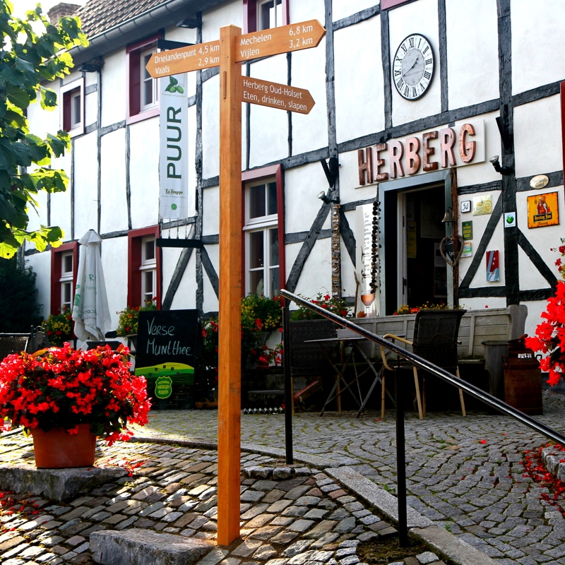 Vooraanzicht van Herberg Oud-Holset met rode bloemen