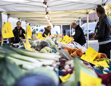 Mensen staan aan een groentekraam op de markt