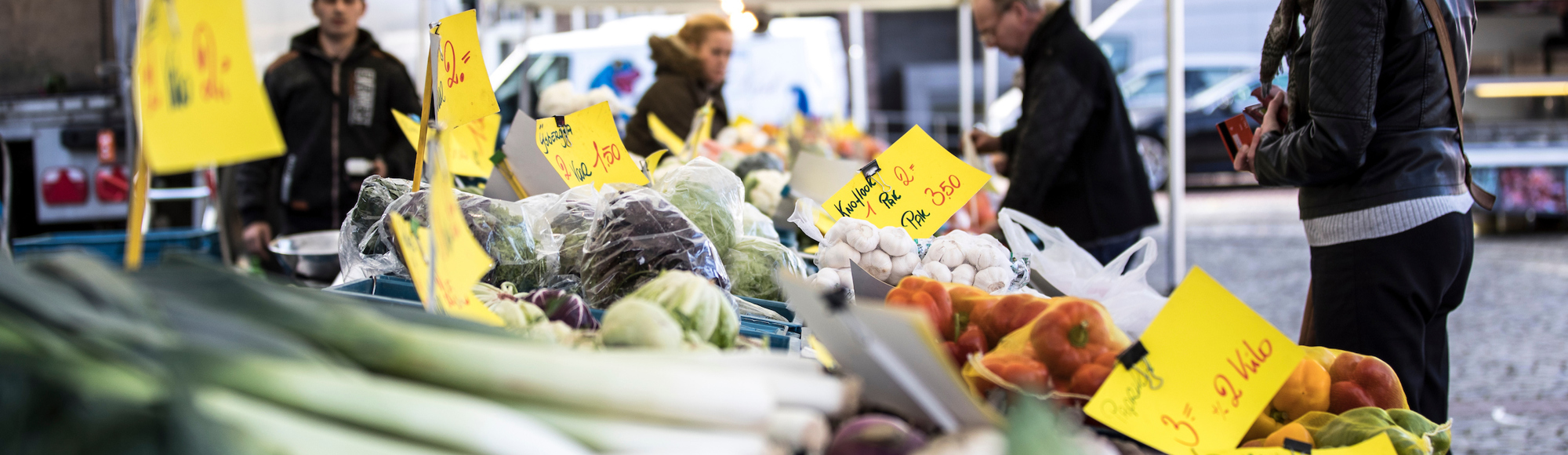 Mensen staan aan een groentekraam op de markt