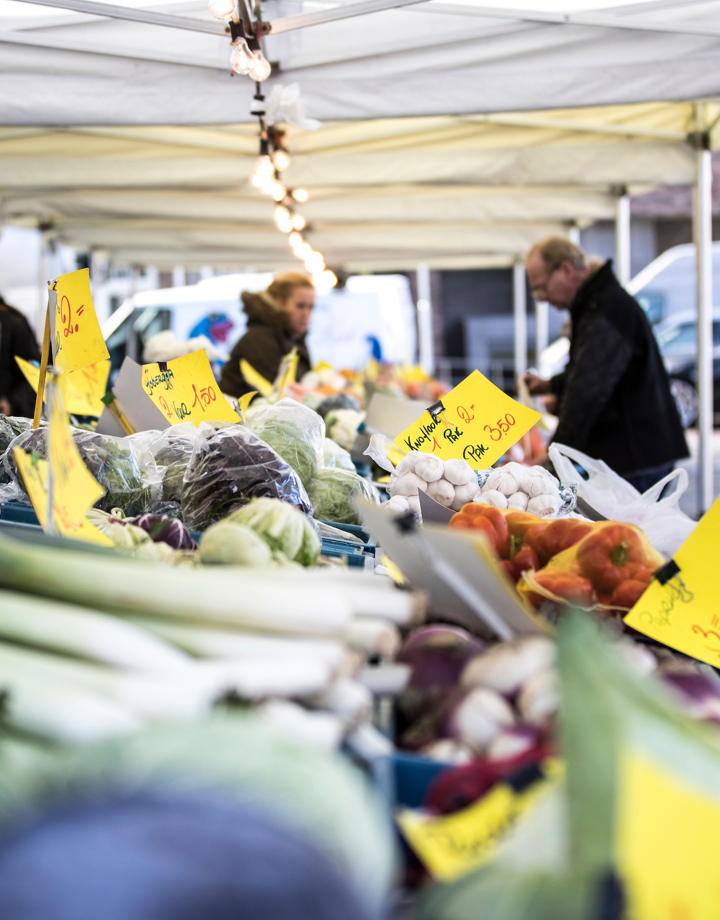 Mensen staan aan een groentekraam op de markt