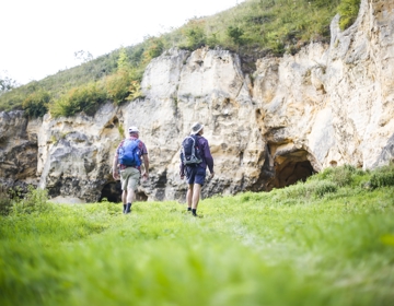Wandelaars lopen over het gras naar mergelwand