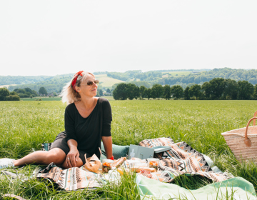 Vrouw zittende op picknickdeken met achterliggend heuvellandschap