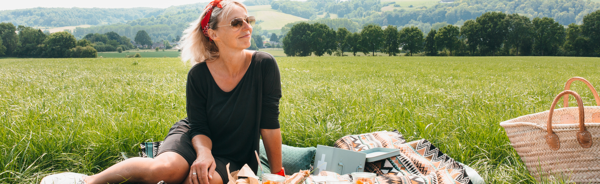 Vrouw zittende op picknickdeken met achterliggend heuvellandschap