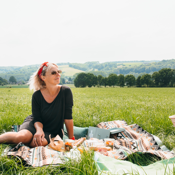 Vrouw zittende op picknickdeken met achterliggend heuvellandschap