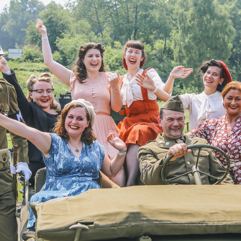 Mensen vieren de bevrijding in Jeep met soldaten en jaren 50 kledij