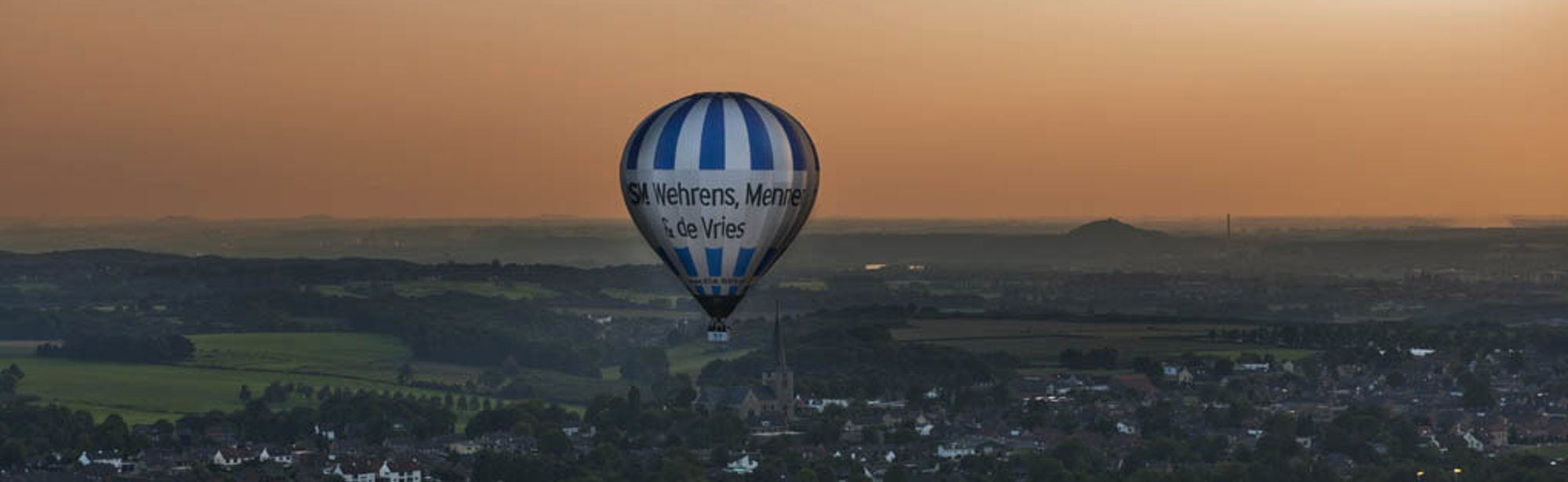 Luchtballon Boven Zuid Limburgs Heuvelland met een oranje lucht