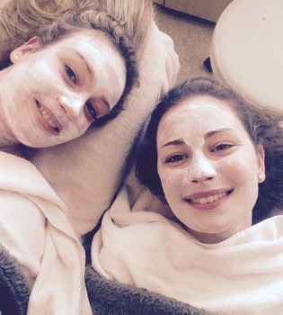 Selfie van twee dames met een maskertje op tijdens een beautybehandeling. 