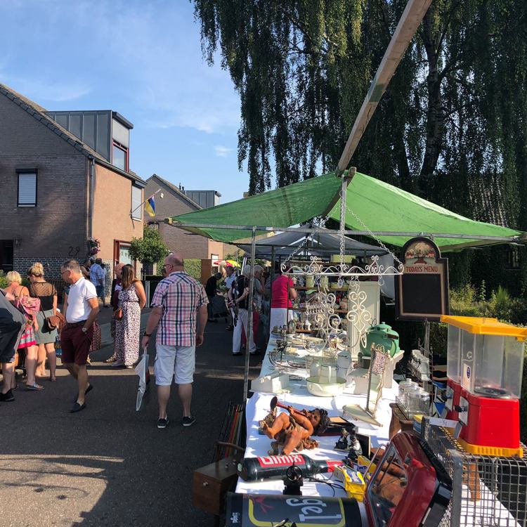 Mensen struinen langs marktkraampjes met brocante