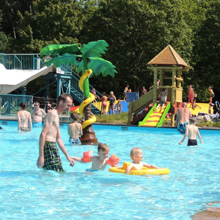 Volwassenen en kinderen hebben plezier in het buitenbad in de zomer bij het Steinerbos