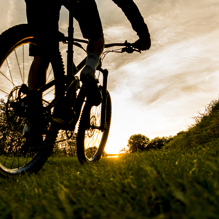 Een close up van de mountainbike wielen en gras tijdens een zonsondergang