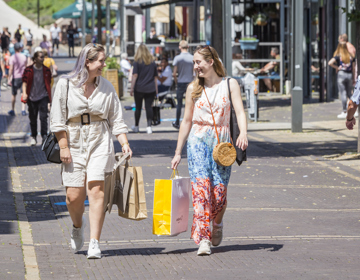 Twee meiden lopen al lachend met een winkeltasje door de winkelstraten van Heerlen