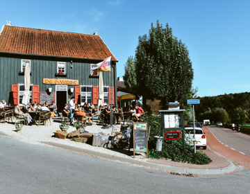 Een authentieke herberg met drukbezocht terras ligt aan een heuvelachtige weg