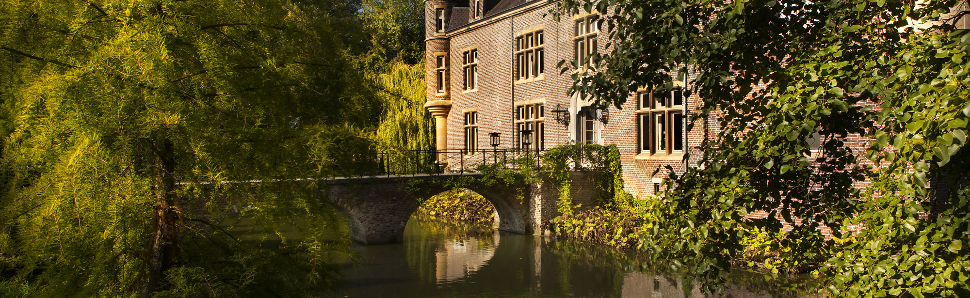 Kasteel Terworm met een brug over de gracht en natuurlijke begroeiing rondom