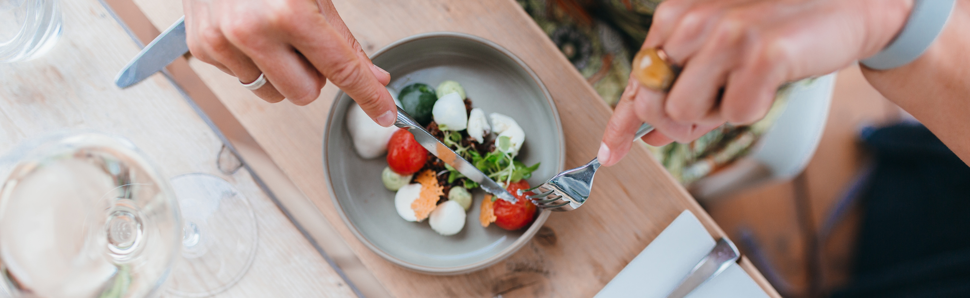 Vrouw snijdt een tomaatje van haar gerecht bij wijnrestaurant Mes Amis